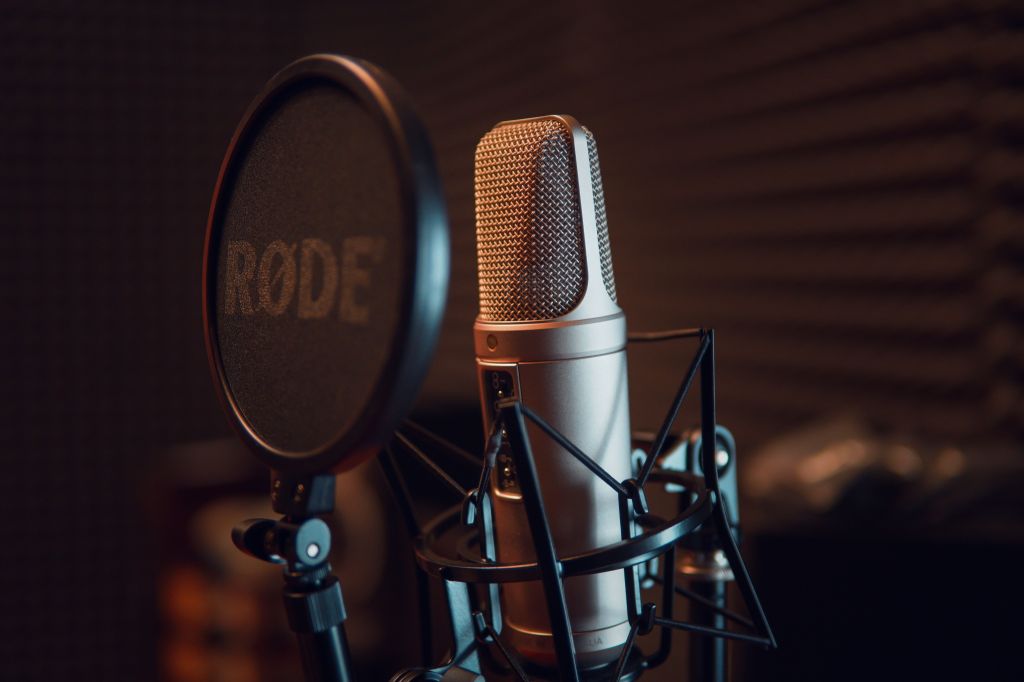 Close-up of a studio condenser microphone and pop filter in a recording booth