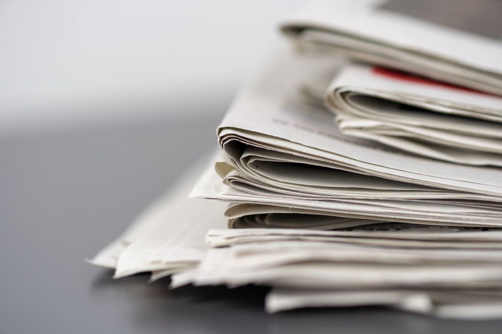 A stack of folded print newspapers on a table