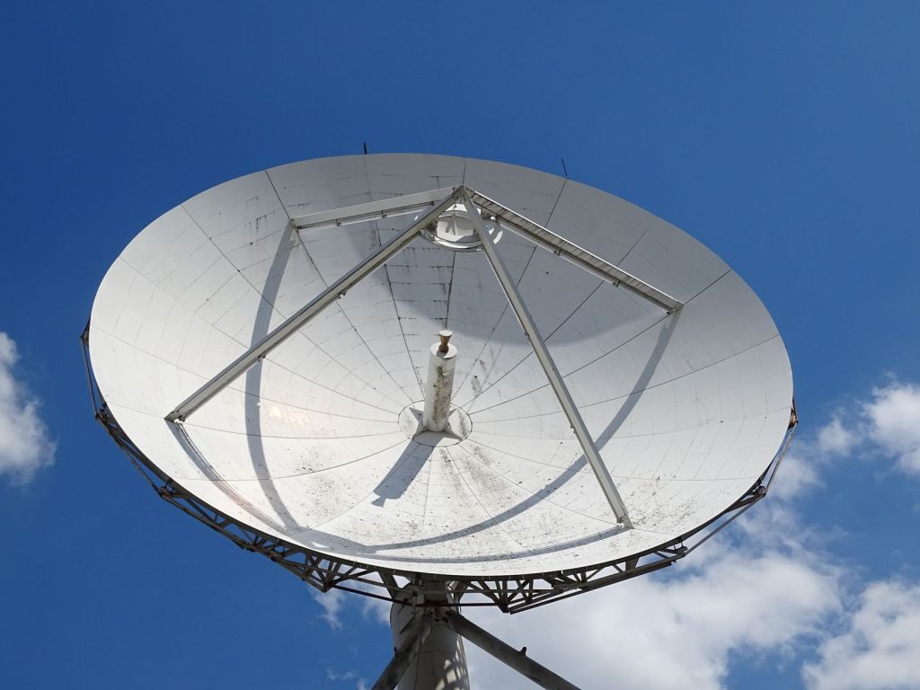 Large white satellite dish pointed at a blue sky with clouds