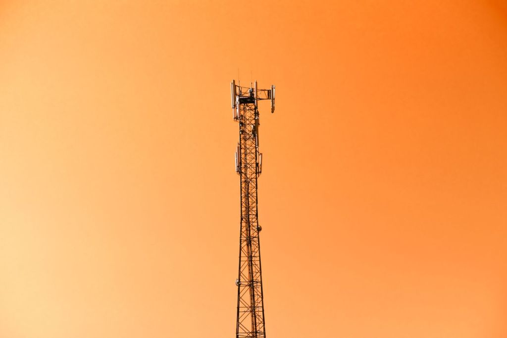 A broadcast radio mast against an orange sunset sky