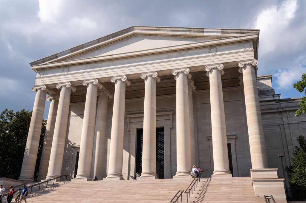 Neoclassical stone building with tall columns and wide steps under a cloudy sky