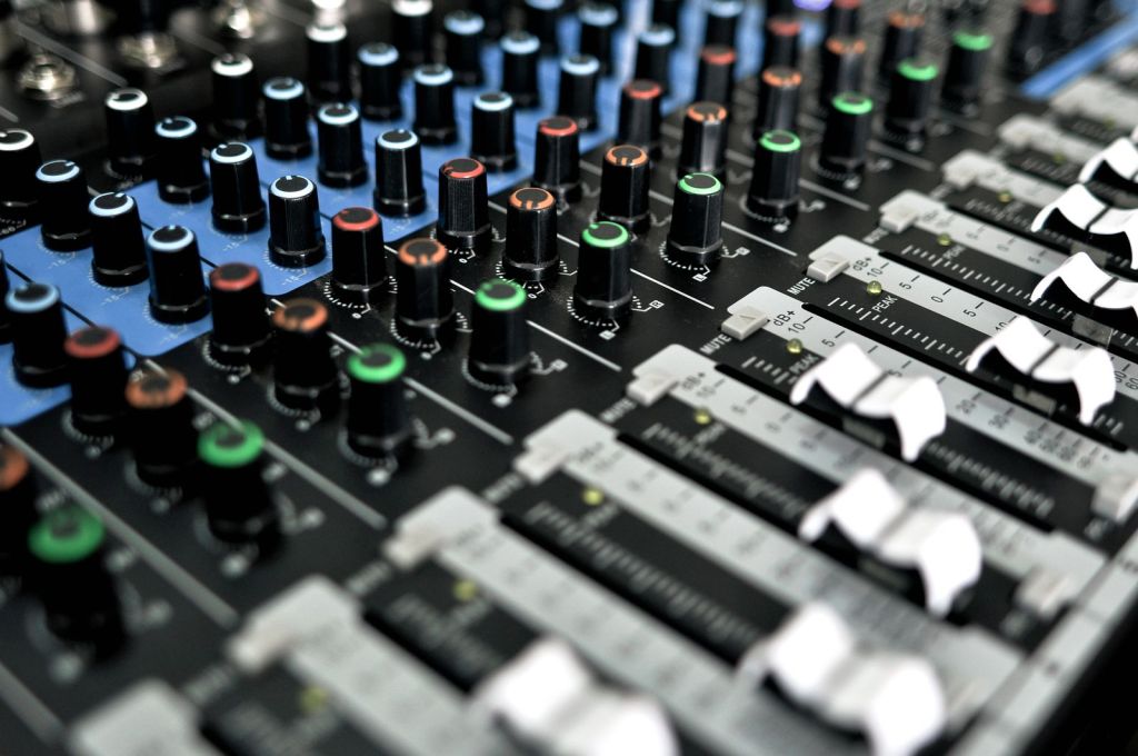 Close-up of an audio mixing console with faders and knobs in a broadcast studio