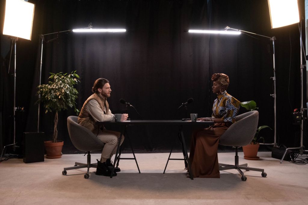 Two hosts recording a video podcast in a studio with lights and microphones