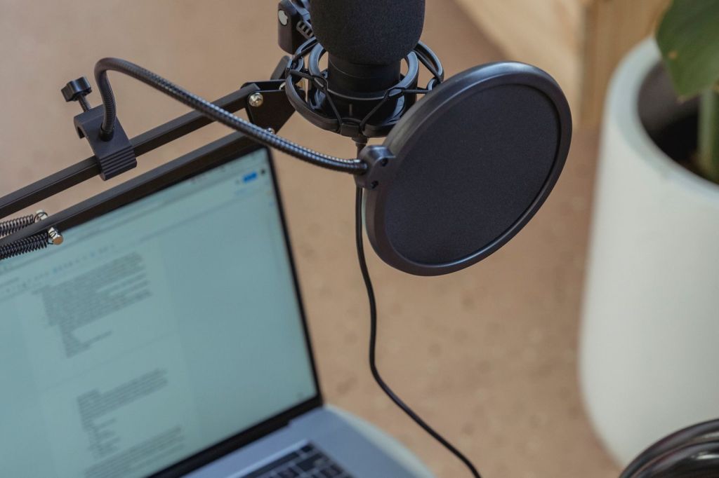 Podcast microphone with pop filter in front of a laptop