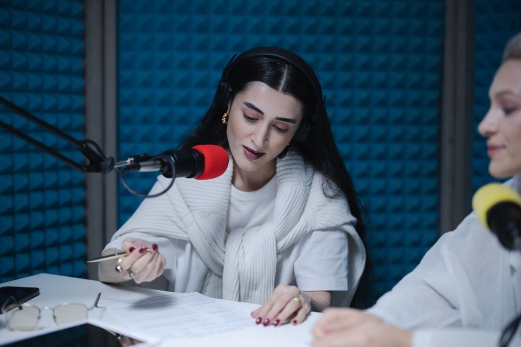 Two radio hosts speaking into microphones in a soundproofed broadcast studio