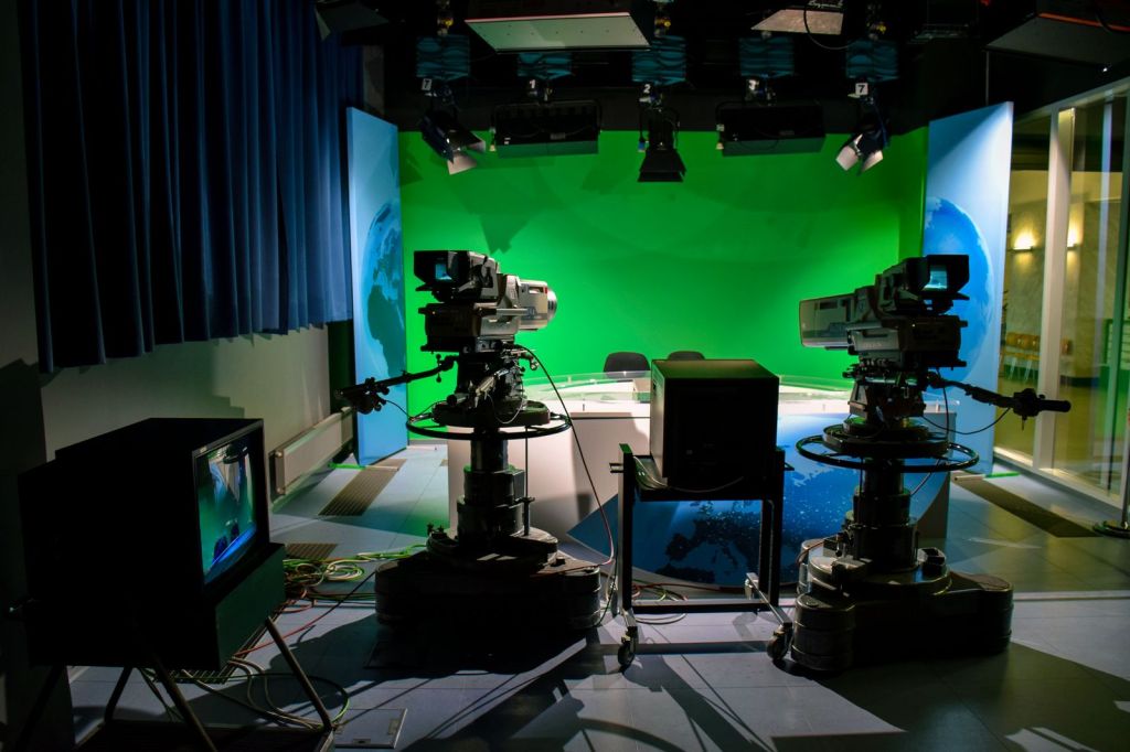 An empty television studio with broadcast cameras aimed at a green screen set