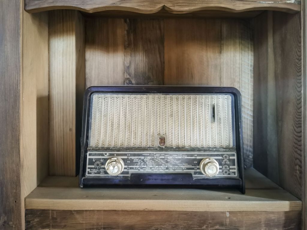 A vintage tube radio sitting on a rustic wooden shelf